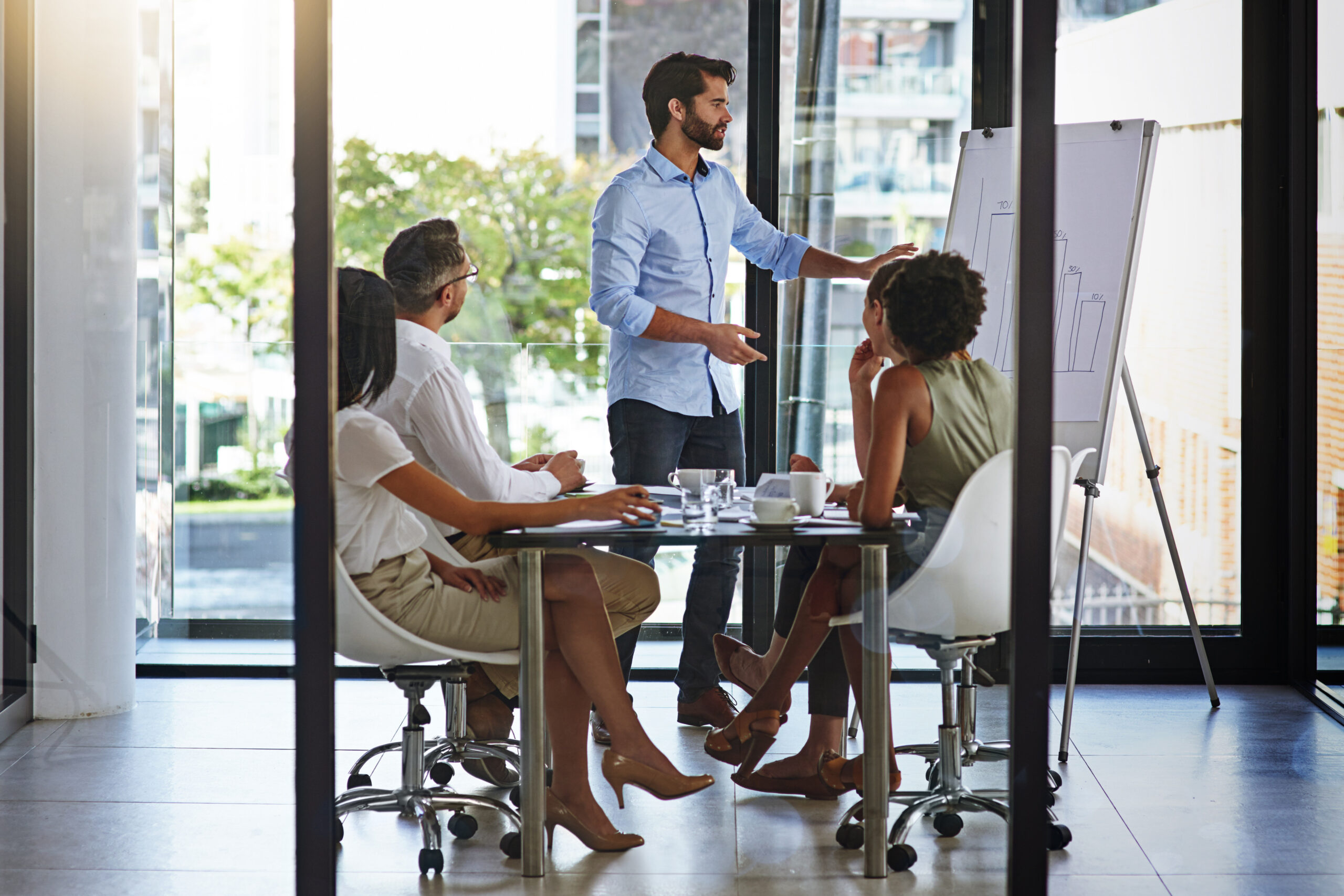 Accueil 3 Réunion d'affaires de cinq personnes devant un tableau blanc, présentation au bureau par un responsable pour un plan financier, une analyse ou une formation.
